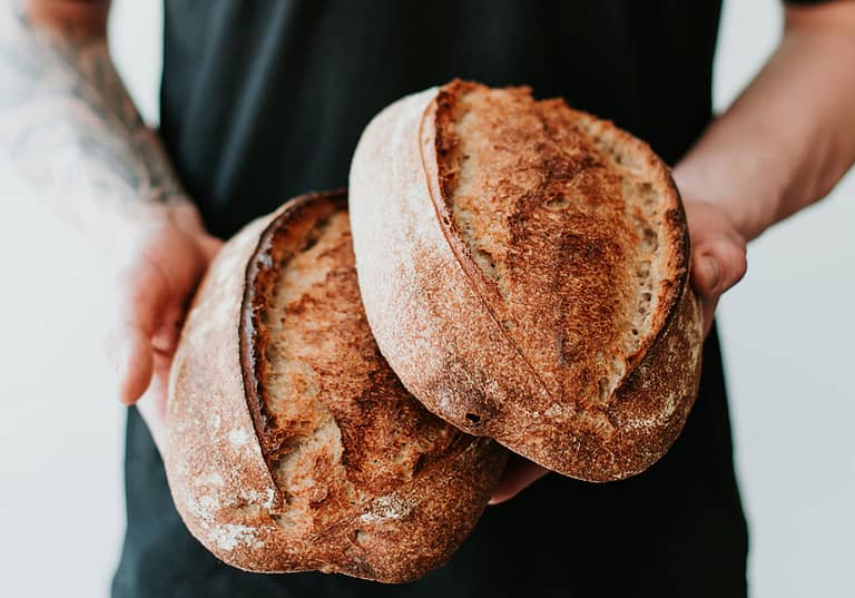 Man holding two loaves of sourdough bread