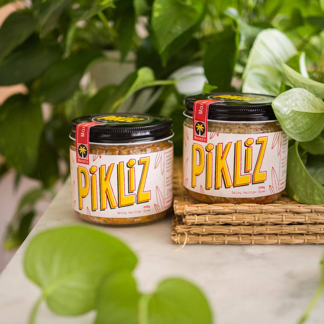 Two jars of pikliz photographed beside some green foliage