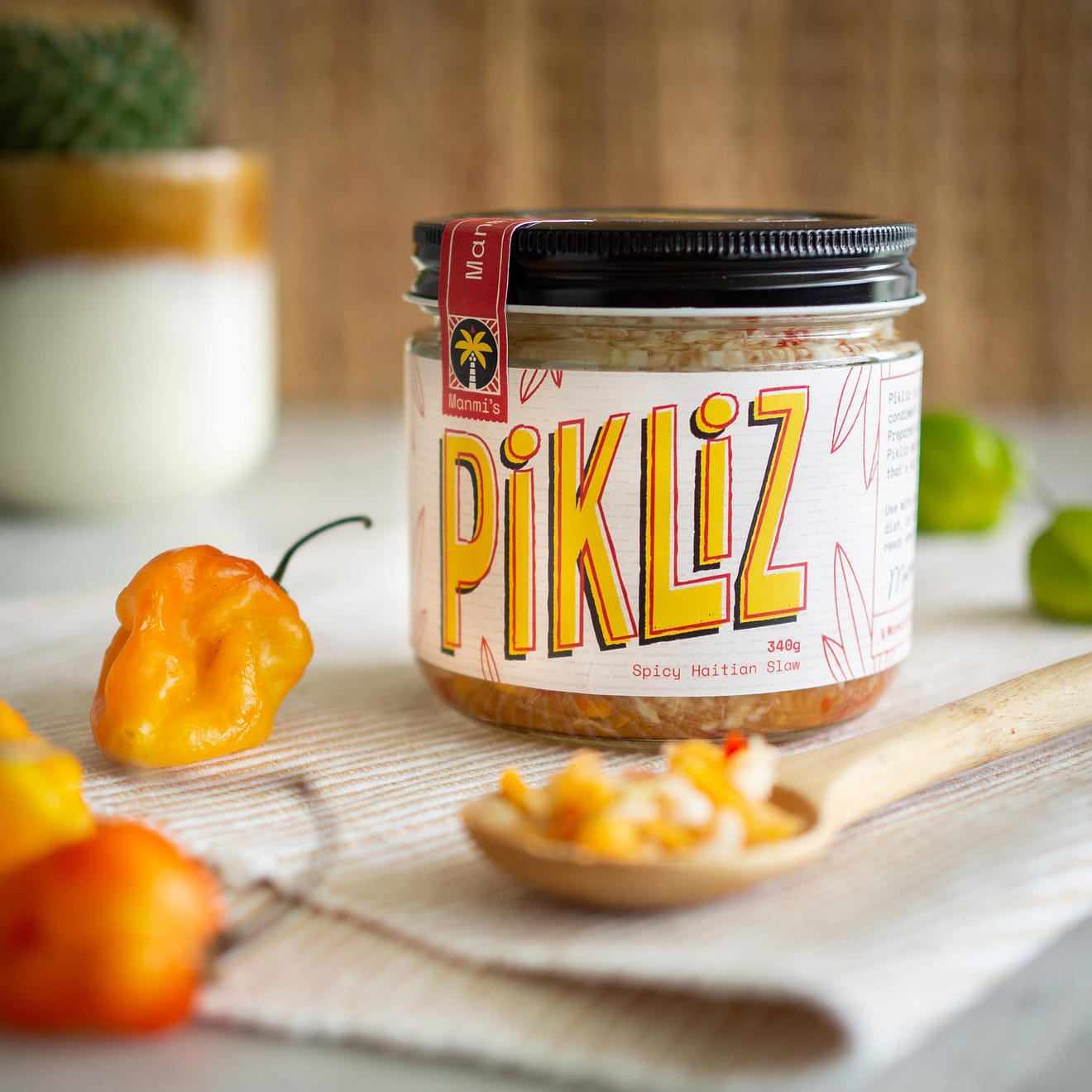 A jar of Pikliz with some scotch bonnet peppers scattered beside it